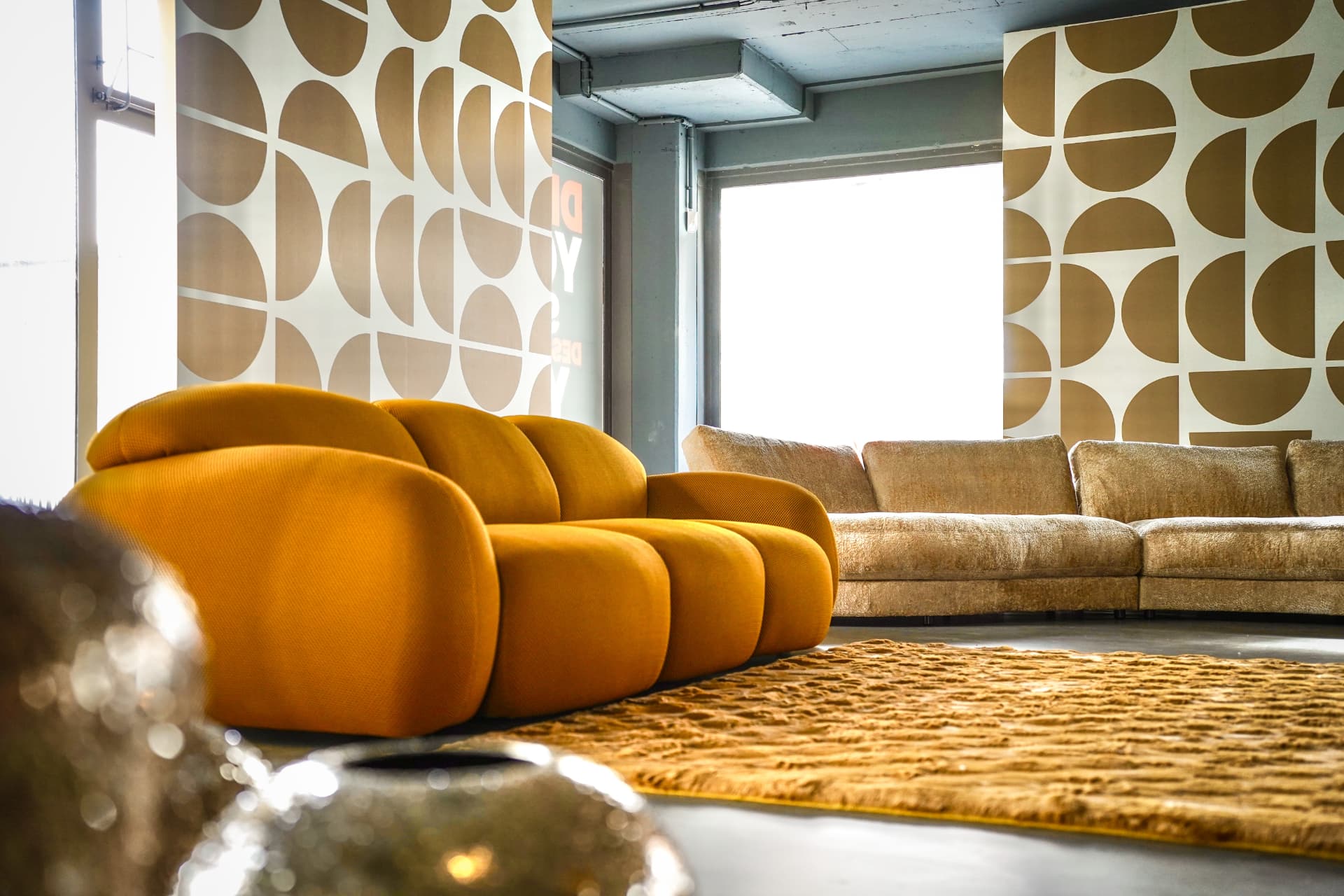 Ausstellungsfläche im House of Kabs mit orangefarbenem Designsofa und grafischer Wandgestaltung