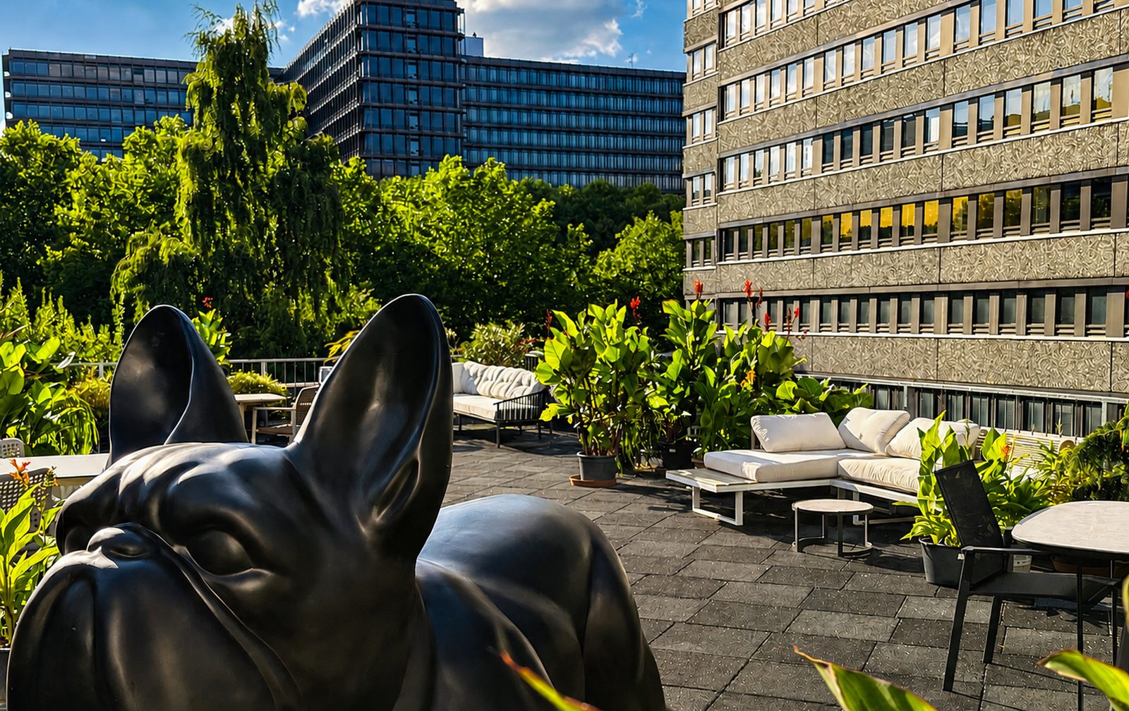 Dachterrasse des De Blanc mit Lounge-Möbeln, Pflanzen und Bulldoggen-Skulptur